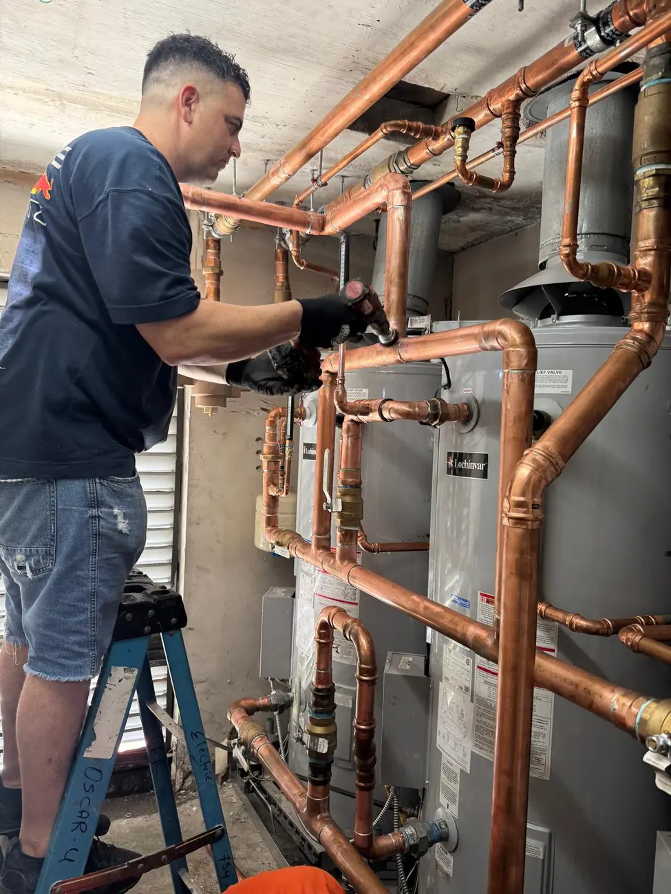 Padron Plumbing technician working on copper piping above commercial water heaters
