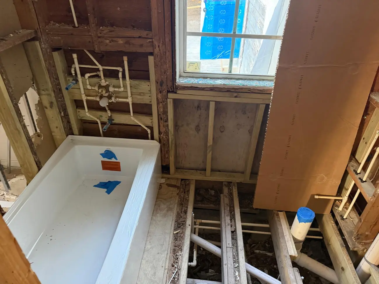 New bathtub set with supply and drain lines roughed in below the floor